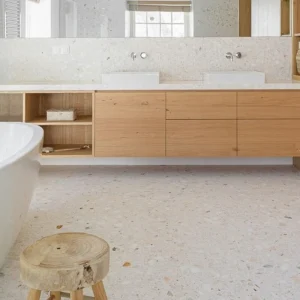 Terrazzo Branco Estremoz Carodeco fond beige clair avec éclats discrets, posé au sol dans une salle de bain moderne