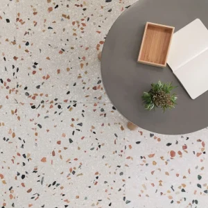 Terrazzo PPG30 Carodeco fond beige clair avec éclats noir, terracotta et beige, posé au sol dans un intérieur contemporain